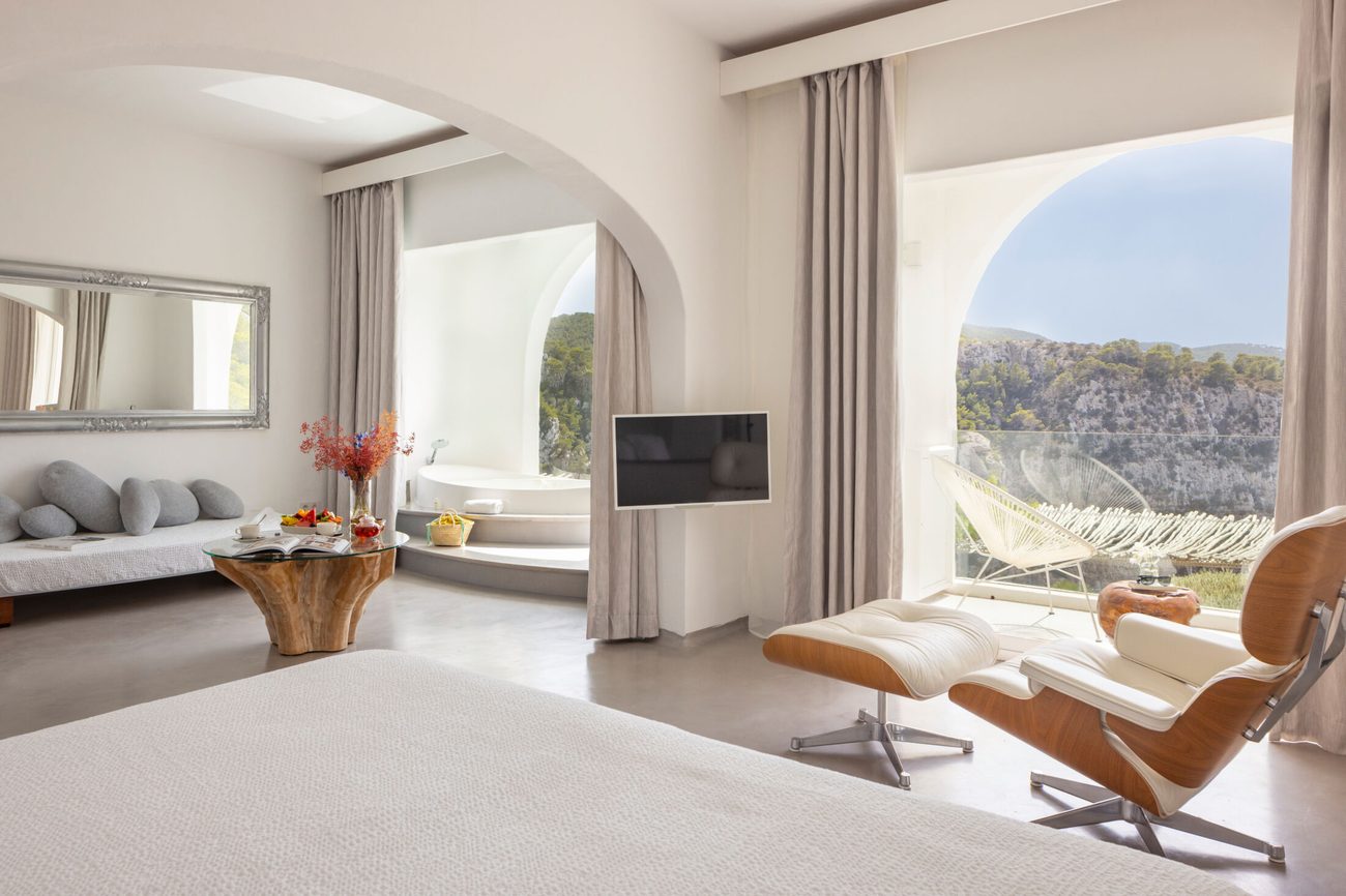 A whitewashed suite with an arched window over the sea