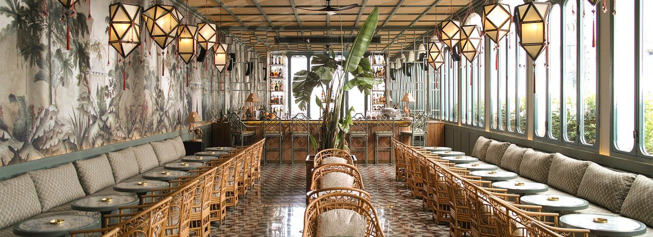 The ninth-floor restaurant, rattan chairs and lantern light against a painted mural