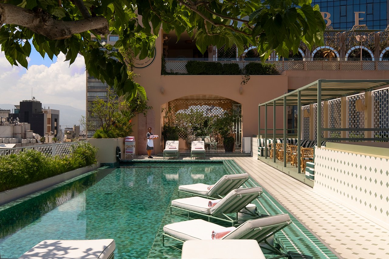 The rooftop pool with loungers under a fig tree and the Beirut skyline beyond