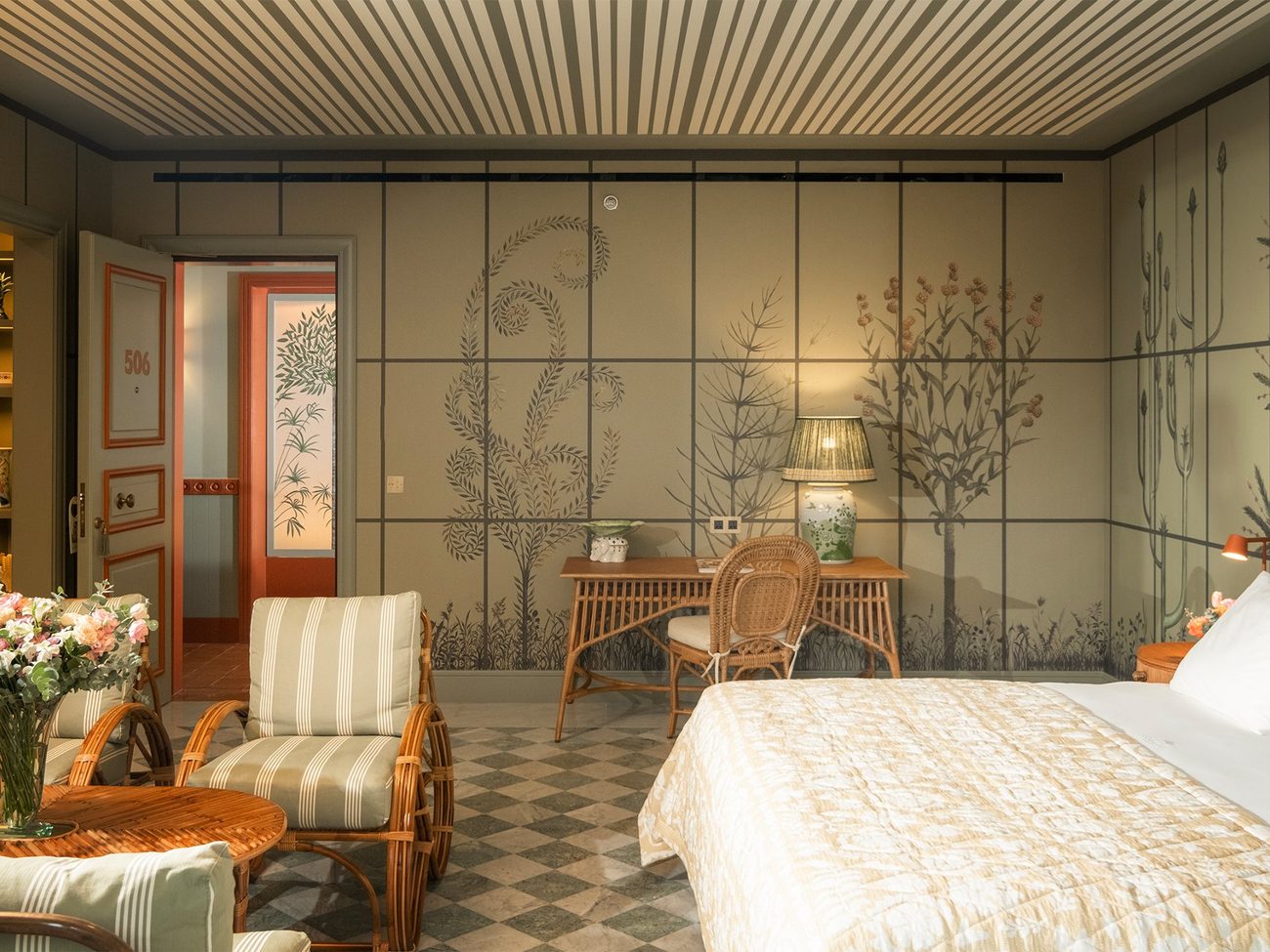 A suite papered in painted lotus flowers above a red striped headboard