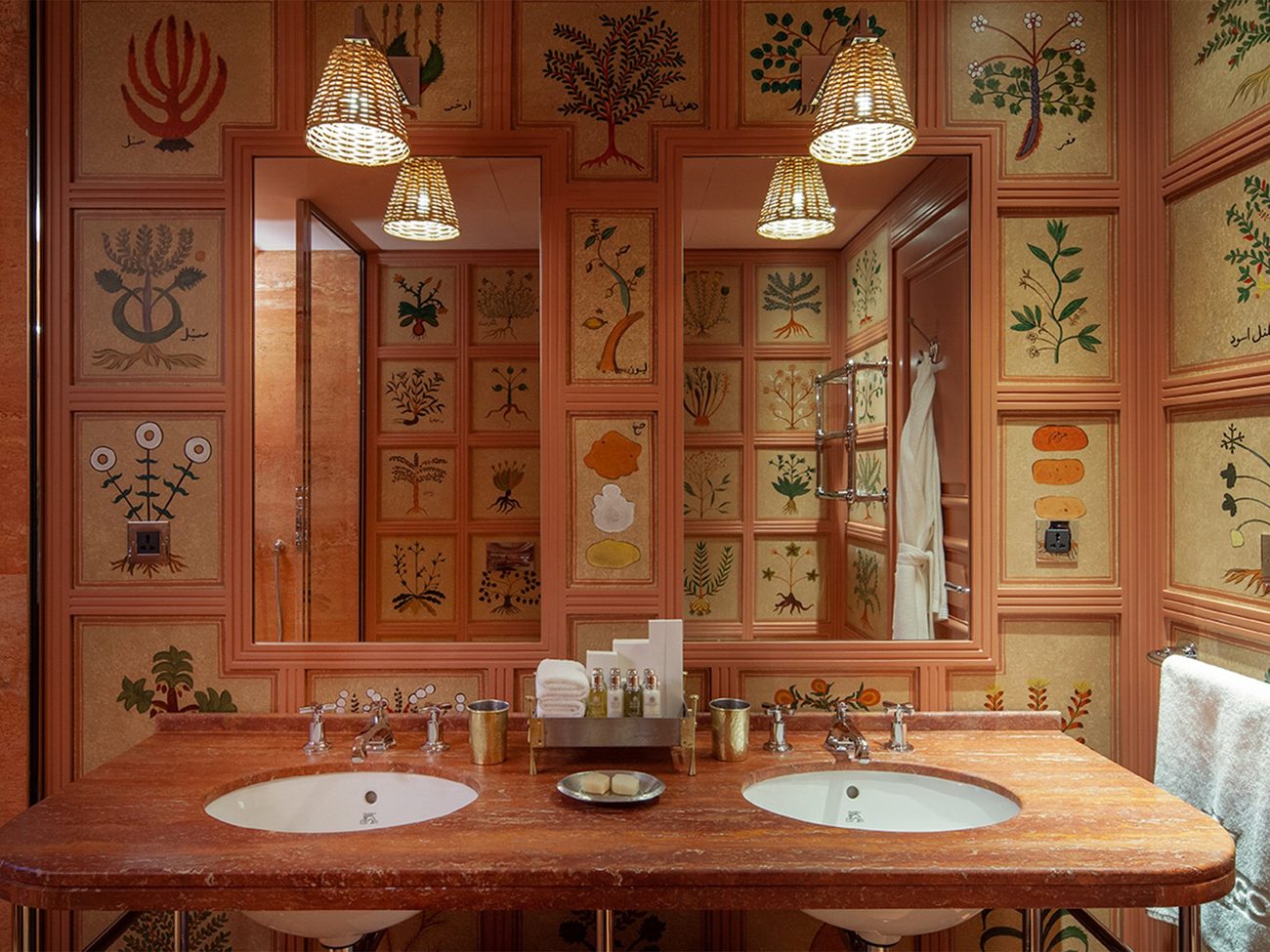 A bathroom lined with hand-drawn botanical panels in coral and green