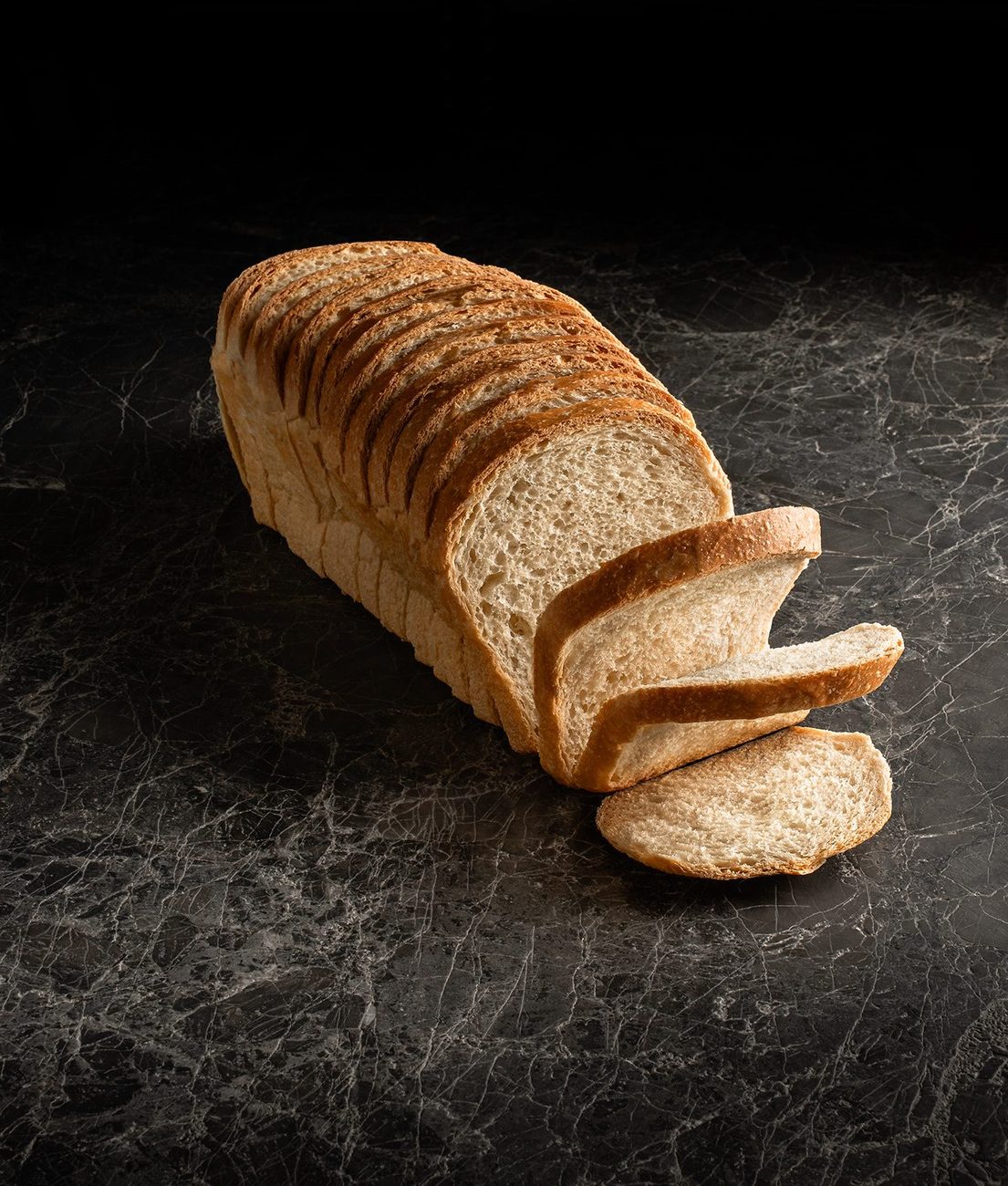 A sourdough loaf cut into slices, showing the open fermented crumb