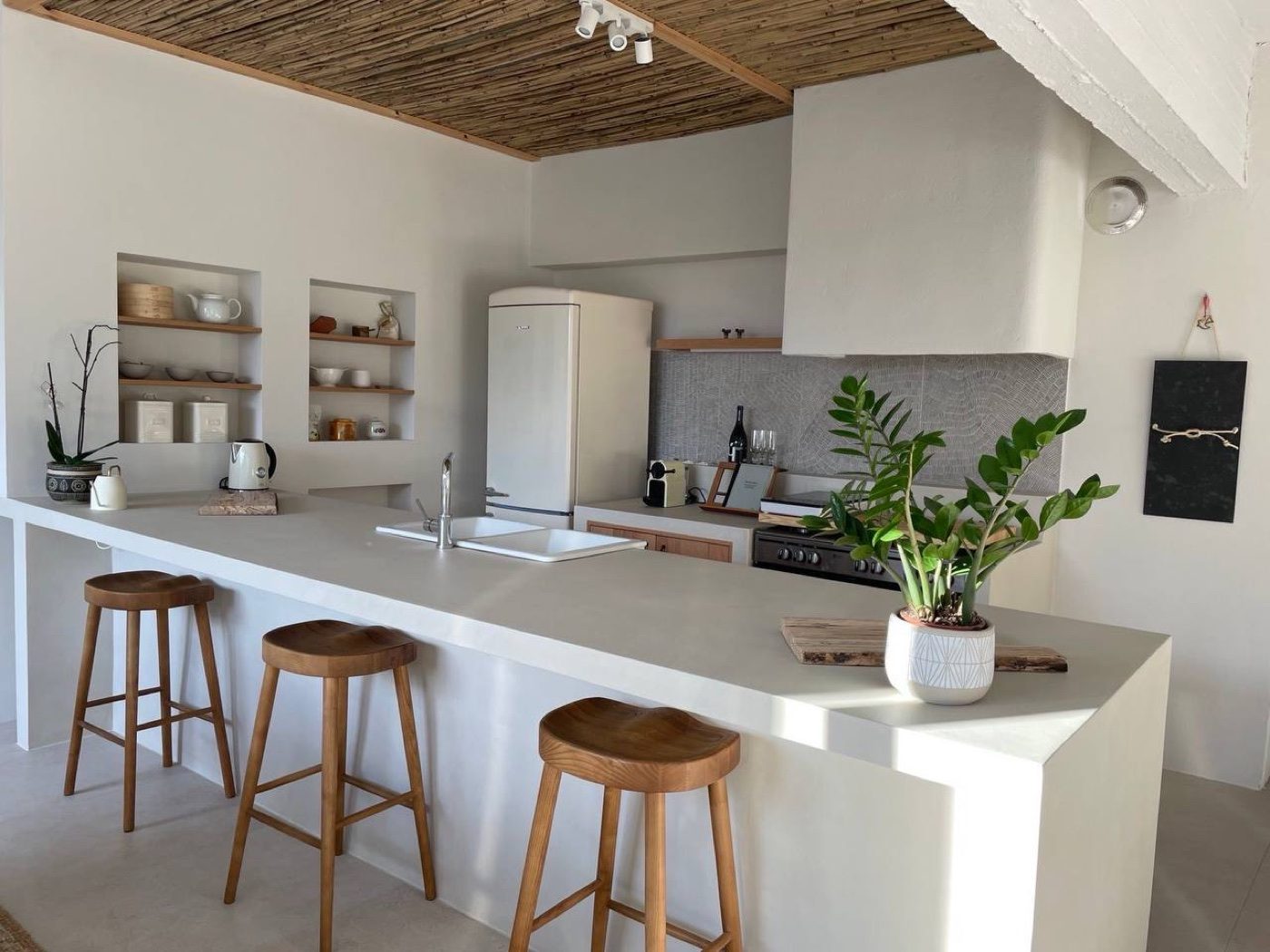 The kitchen at Casa Massina, a long counter and wooden stools under a reed ceiling