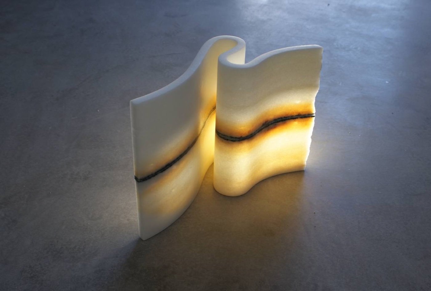 A wave of Naxian marble, backlit so the veined band glows from within