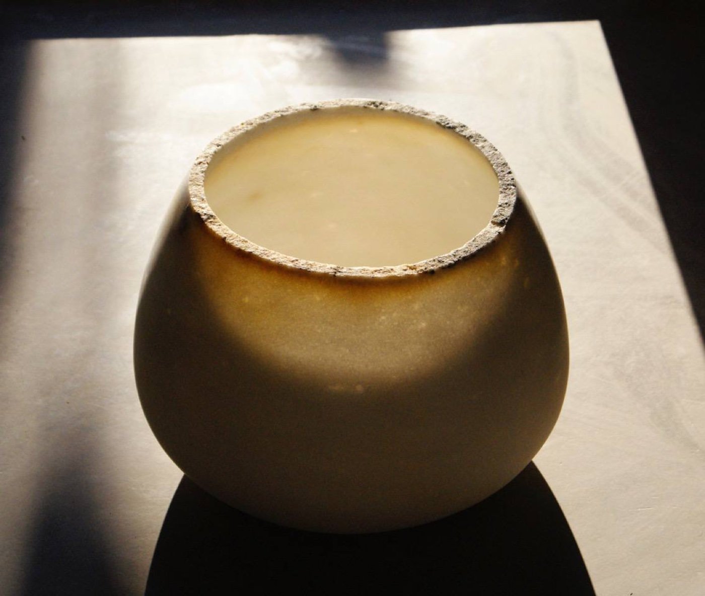 A thin-walled marble bowl on a slab, lit by the sun through the stone