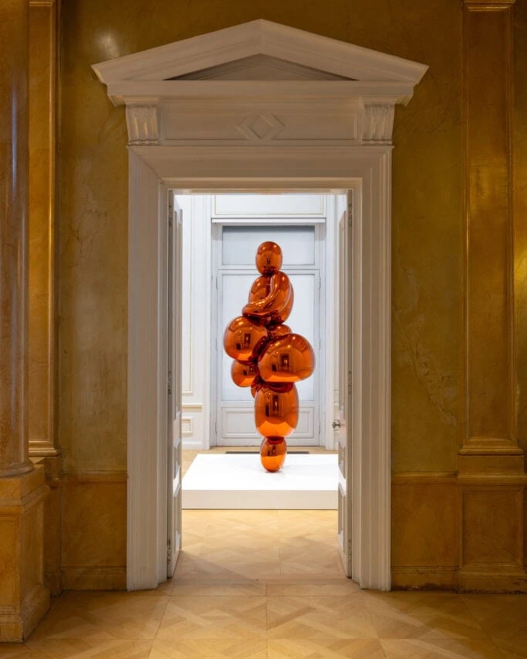 Installation view of Jeff Koons's orange Balloon Venus Lespugue framed by a doorway at the Museum of Cycladic Art