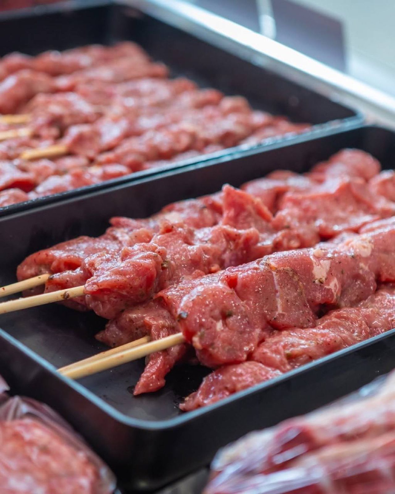 Marinated skewers in trays at the counter, ready for the grill