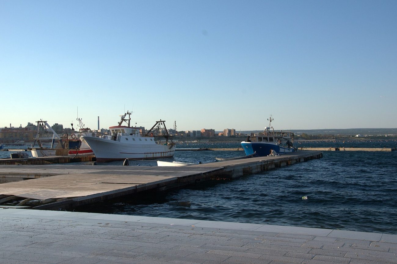 Fishing boats moored beneath the old town of Taranto