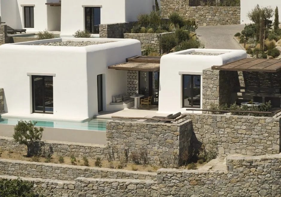 Whitewashed Cycladic villas and stone terraces stepping down the ridge at Kalesma Mykonos