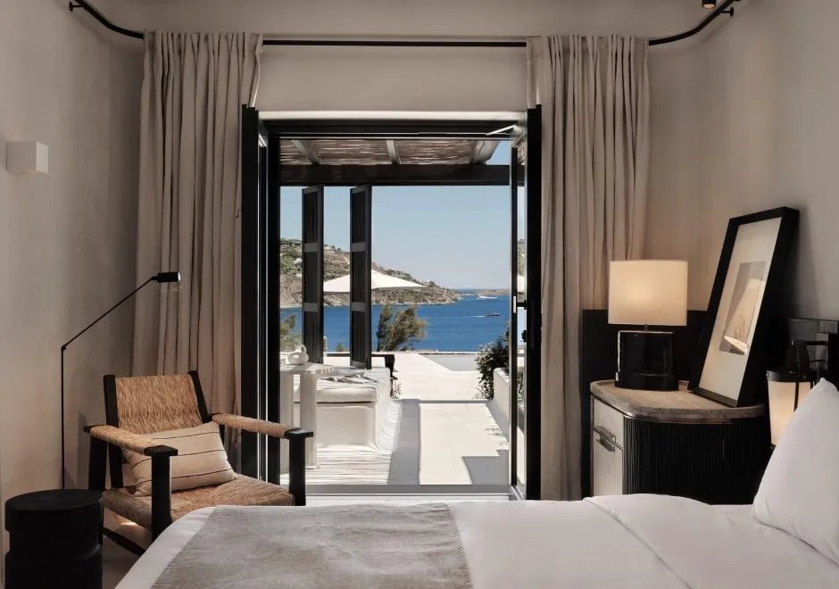 A junior suite at Kalesma Mykonos in linen and pale timber, opening to a sea view