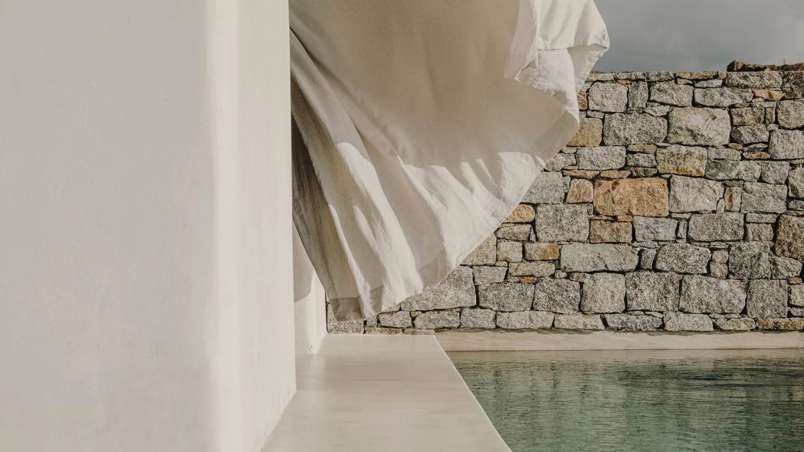 Unbleached linen, dry-stone wall and pool water at Kalesma Mykonos