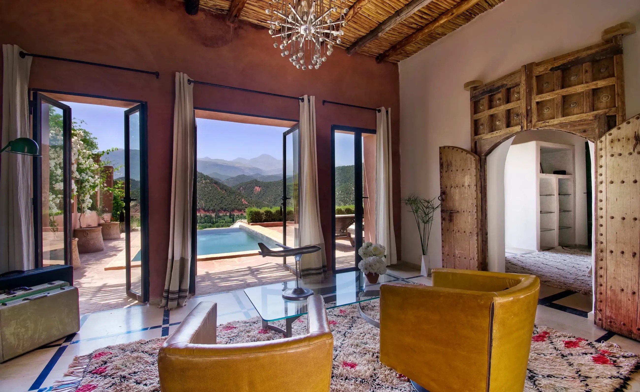 A salon opening through glass doors to a private pool and the mountains beyond