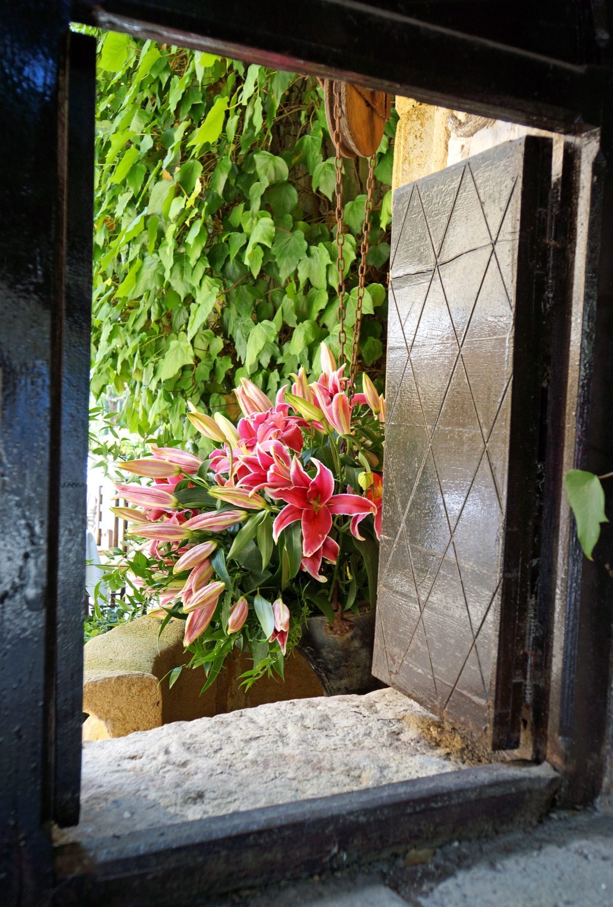 A low doorway framing lilies and ivy in the courtyard