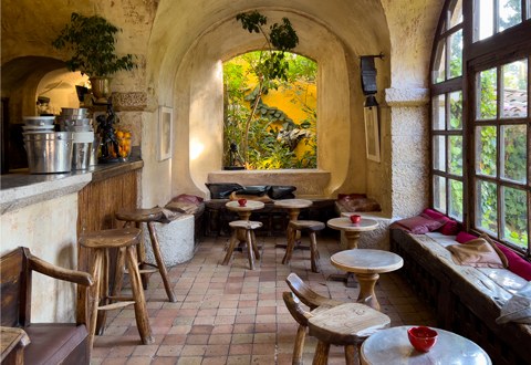 The vaulted stone bar with rustic wooden stools and an arched window onto the garden