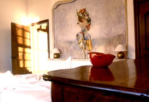 A guest room with a painted wall, a polished wood chest and warm afternoon light