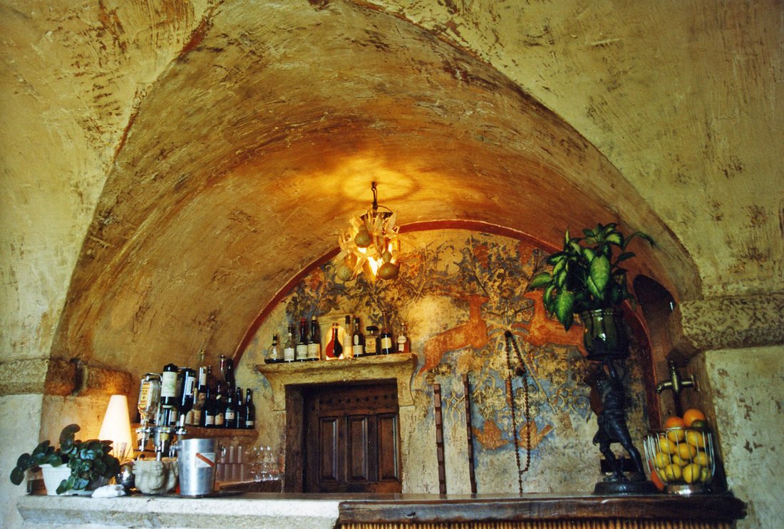 A vaulted dining room with a stone fireplace, a faded fresco and a bowl of lemons