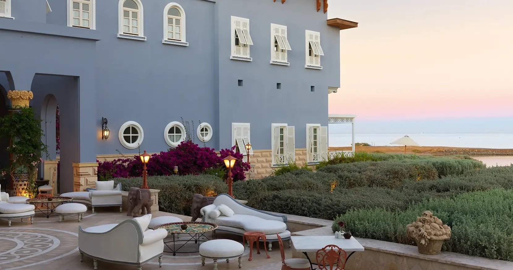A terrace on the blue facade at dusk, the lagoon and the Red Sea beyond