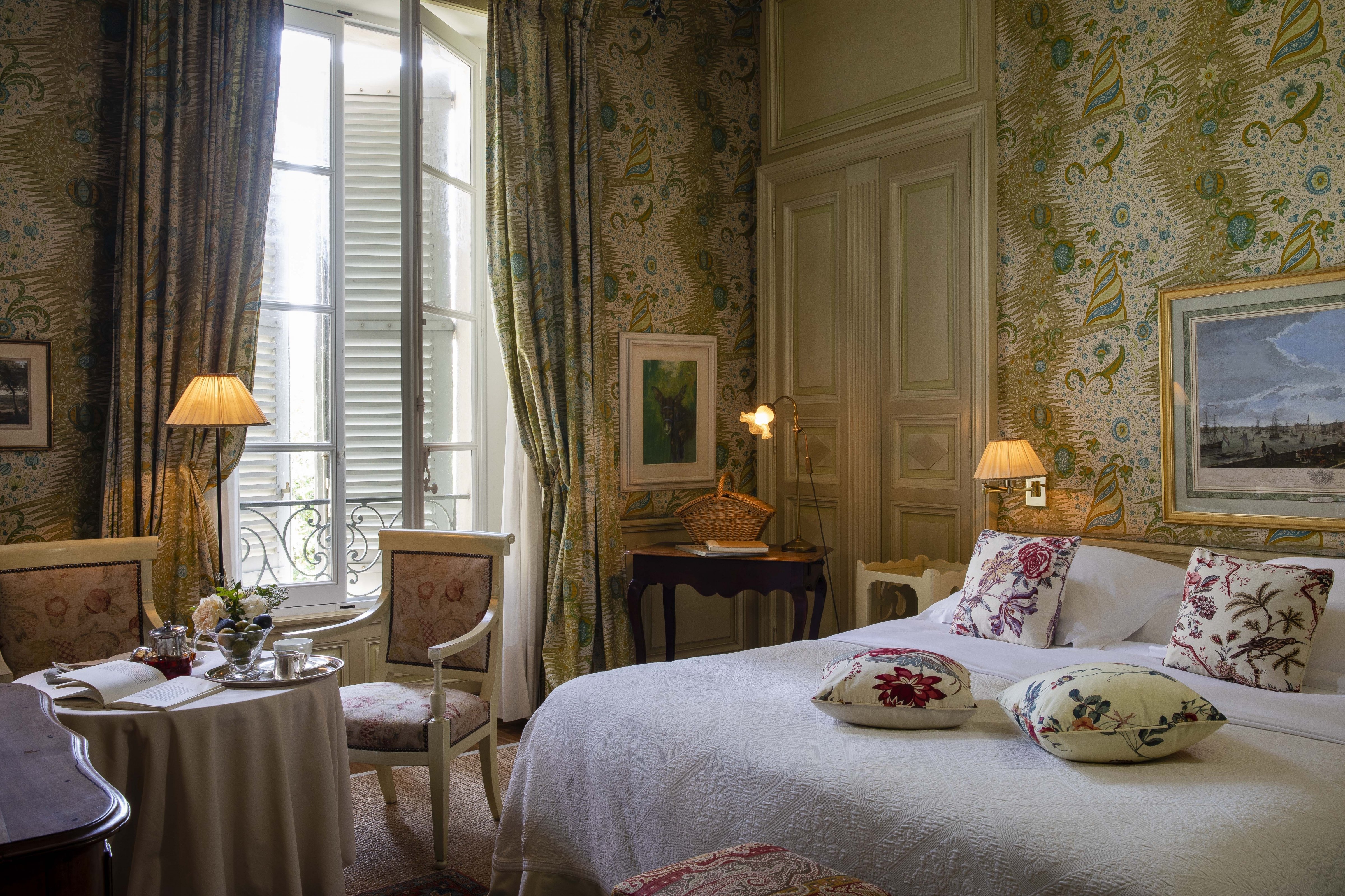 A bedroom dressed in period toile, with shutters onto the old town