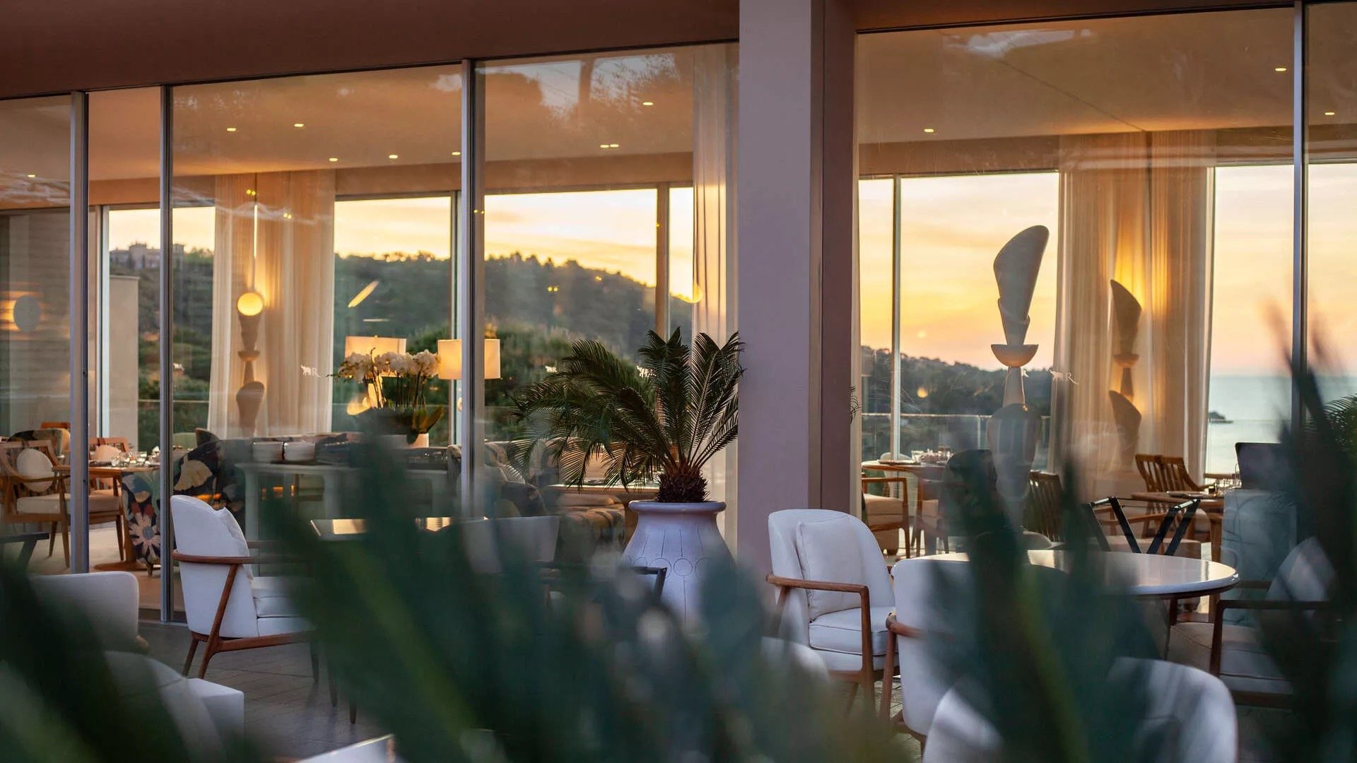 Interiors opening to the terrace as the sun sets over the hills