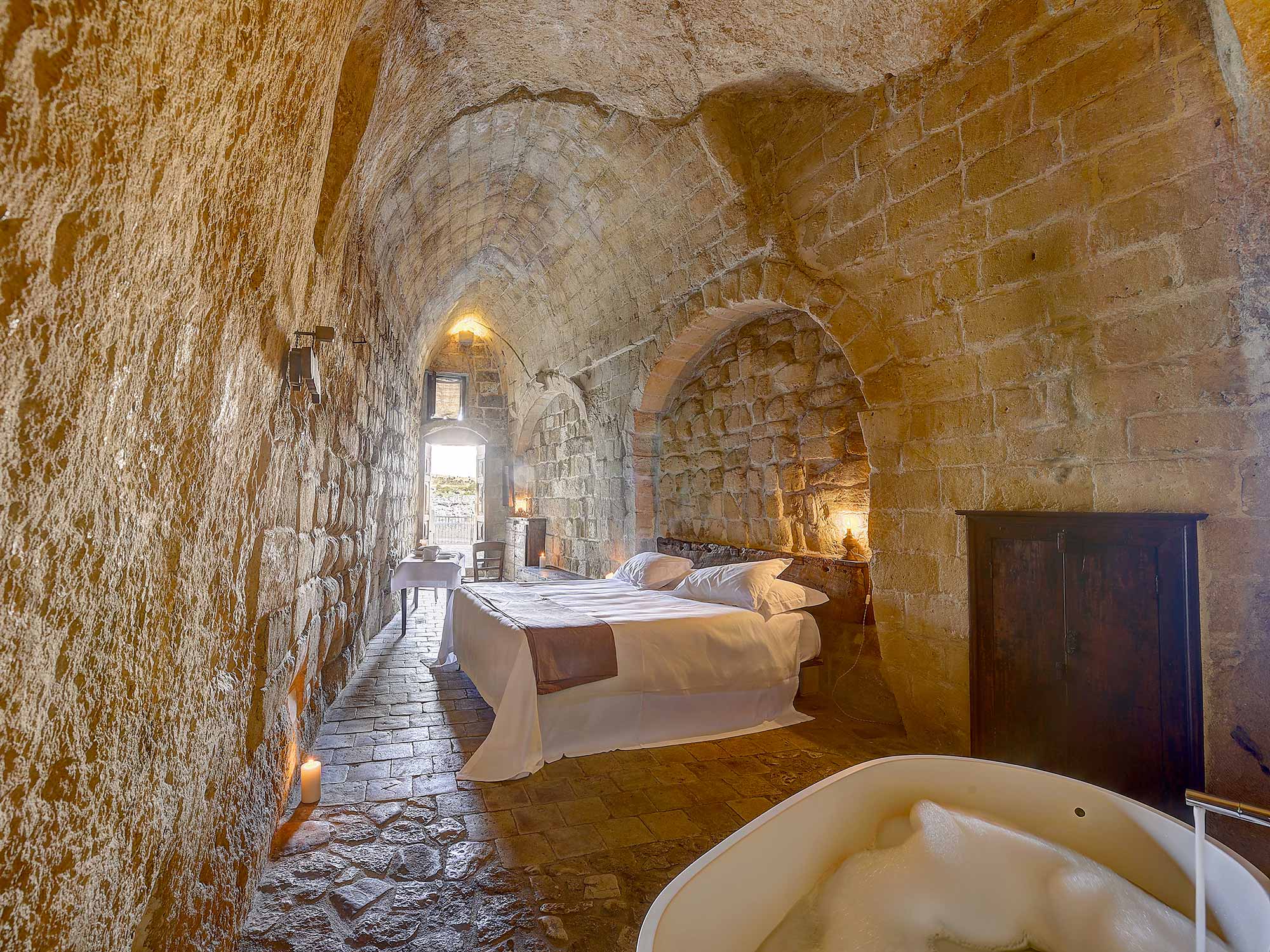A long tunnel-vaulted cave room with a freestanding bath