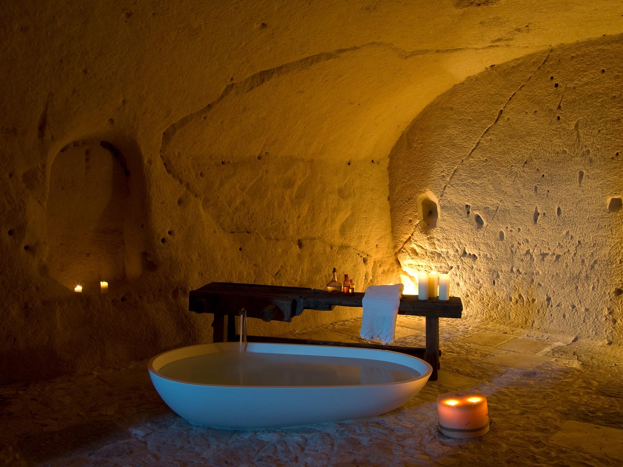 A stone bath by candlelight in a carved grotto