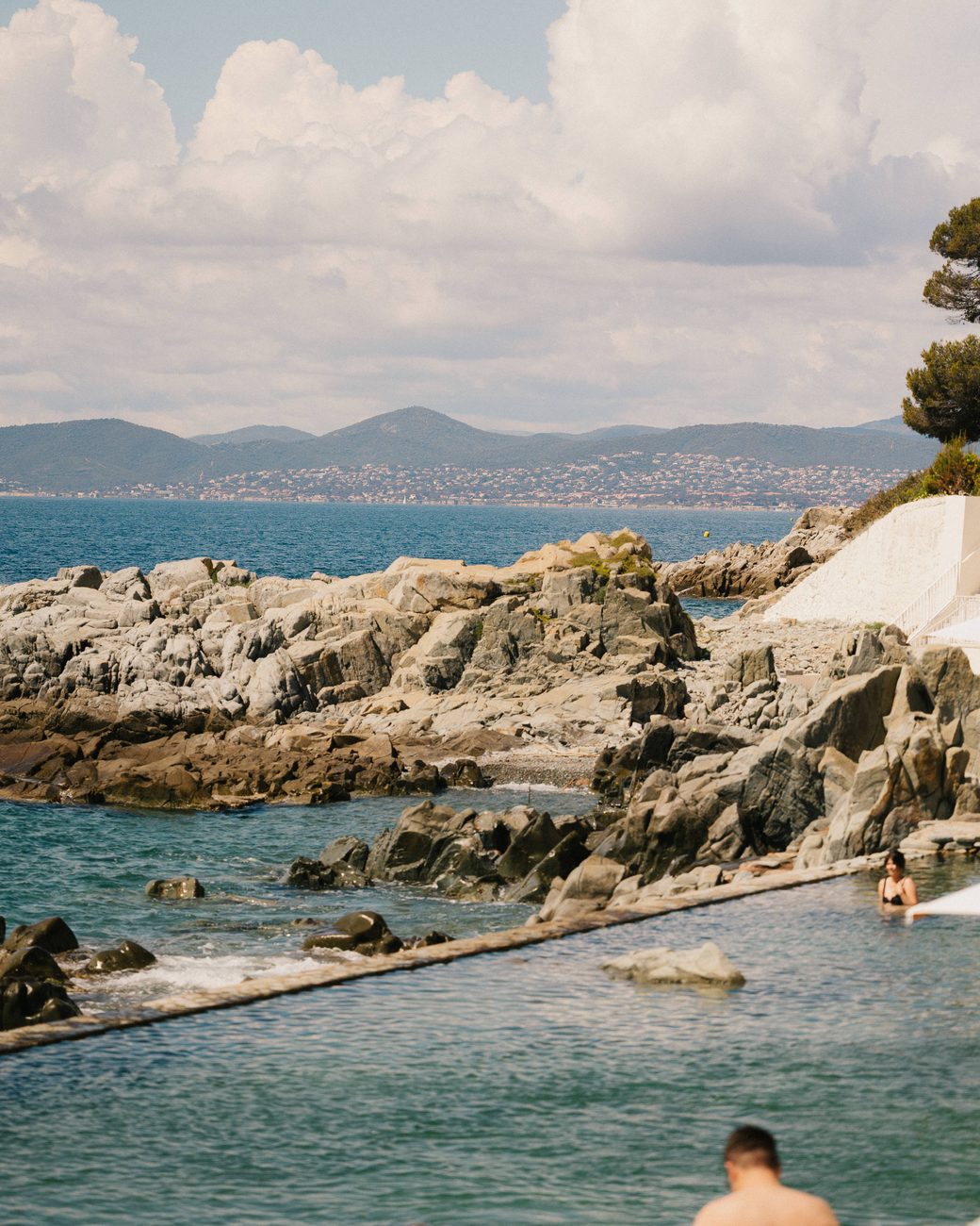The seawater pool cut into the red rocks at the sea's edge, the bay of Saint-Raphaël behind