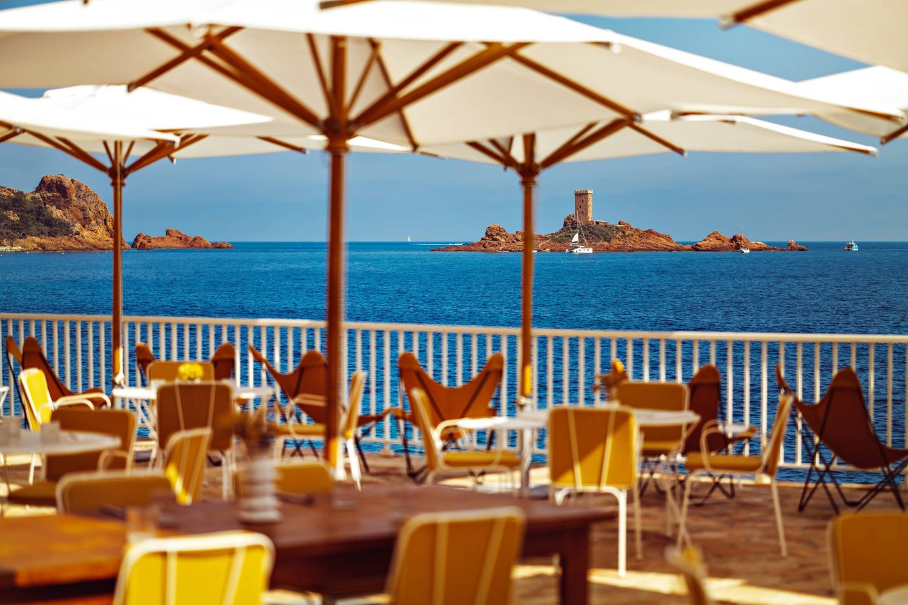 Tables set under white parasols at Estelo, looking out to the tower on the Île d'Or