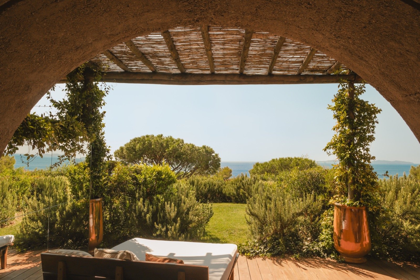 A view through a stone arch to the garden and the sea