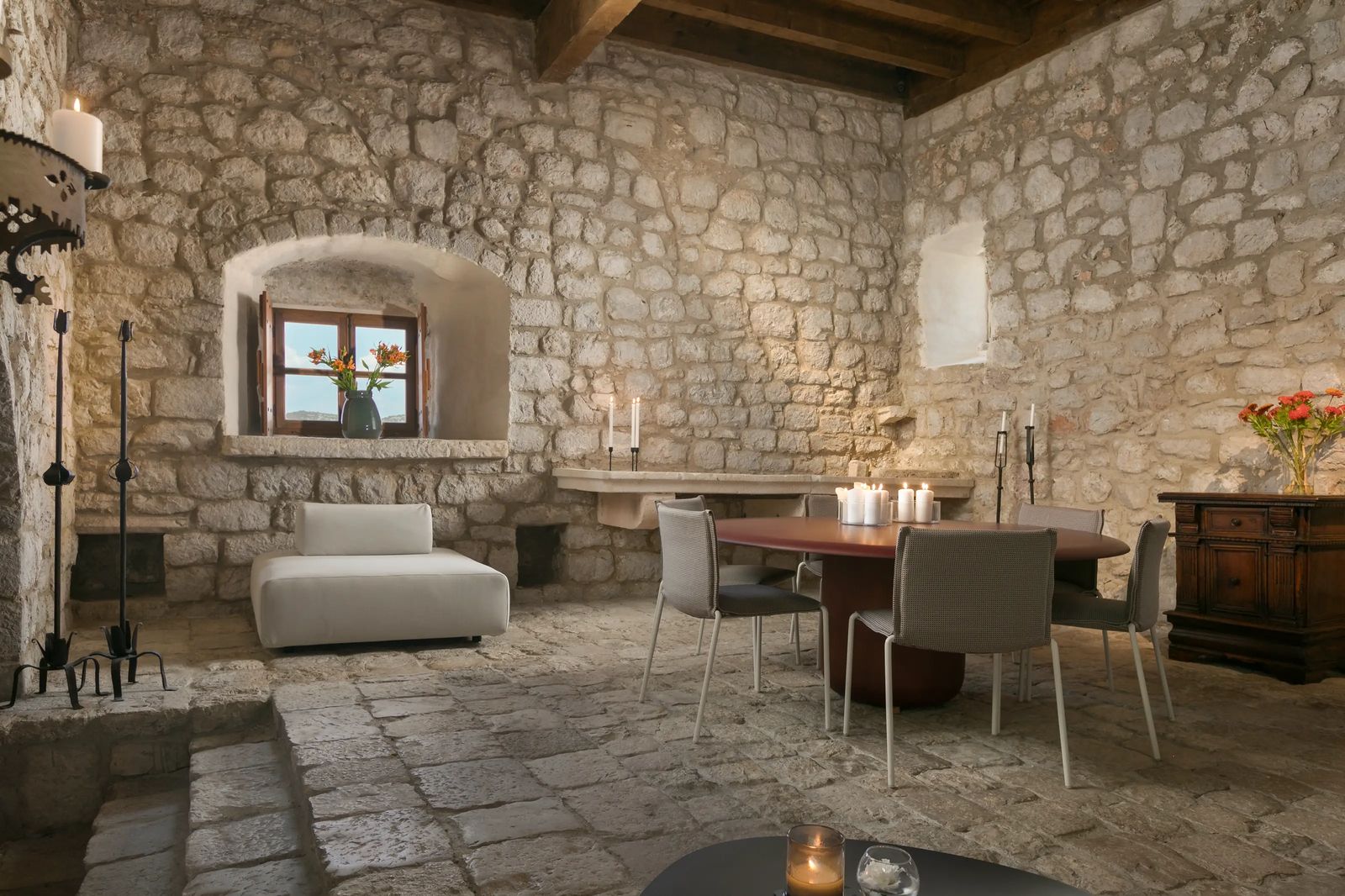 A restored salon inside the monastery, pale stone walls and a fireplace with contemporary furniture