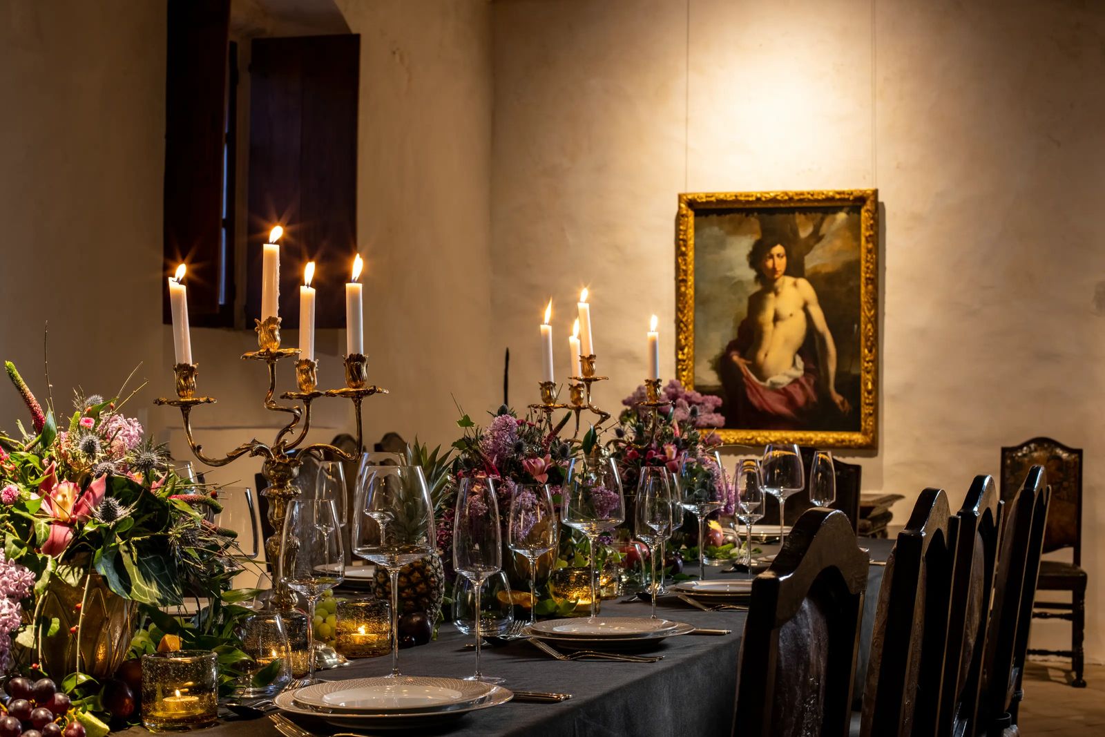 A candlelit dinner laid in the refectory beneath an Old Master painting