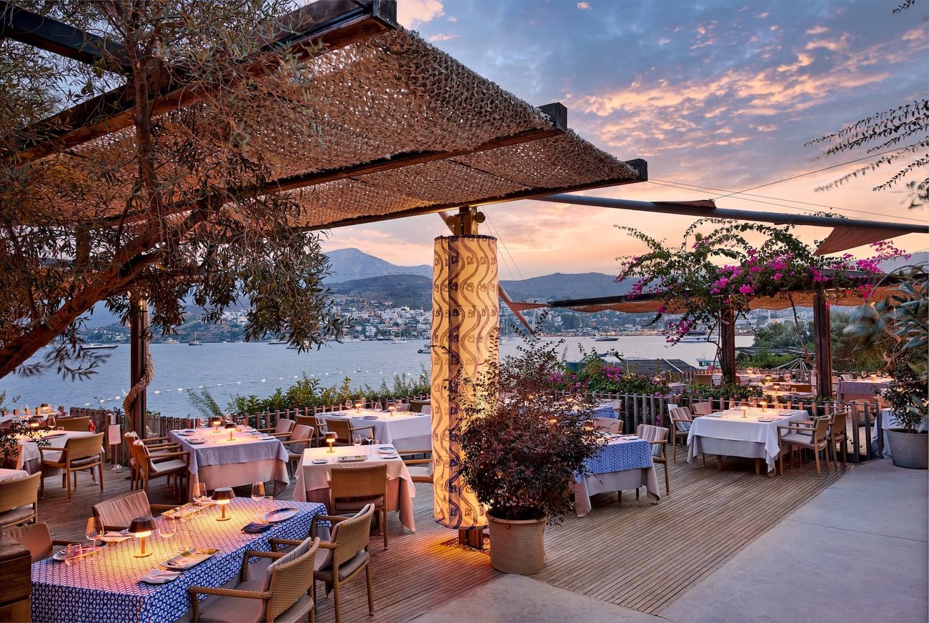 The restaurant terrace at sunset, tables set above the bay