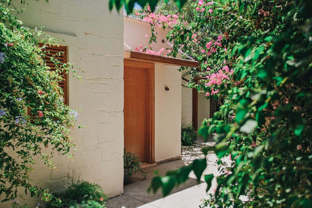 A whitewashed garden room under bougainvillea