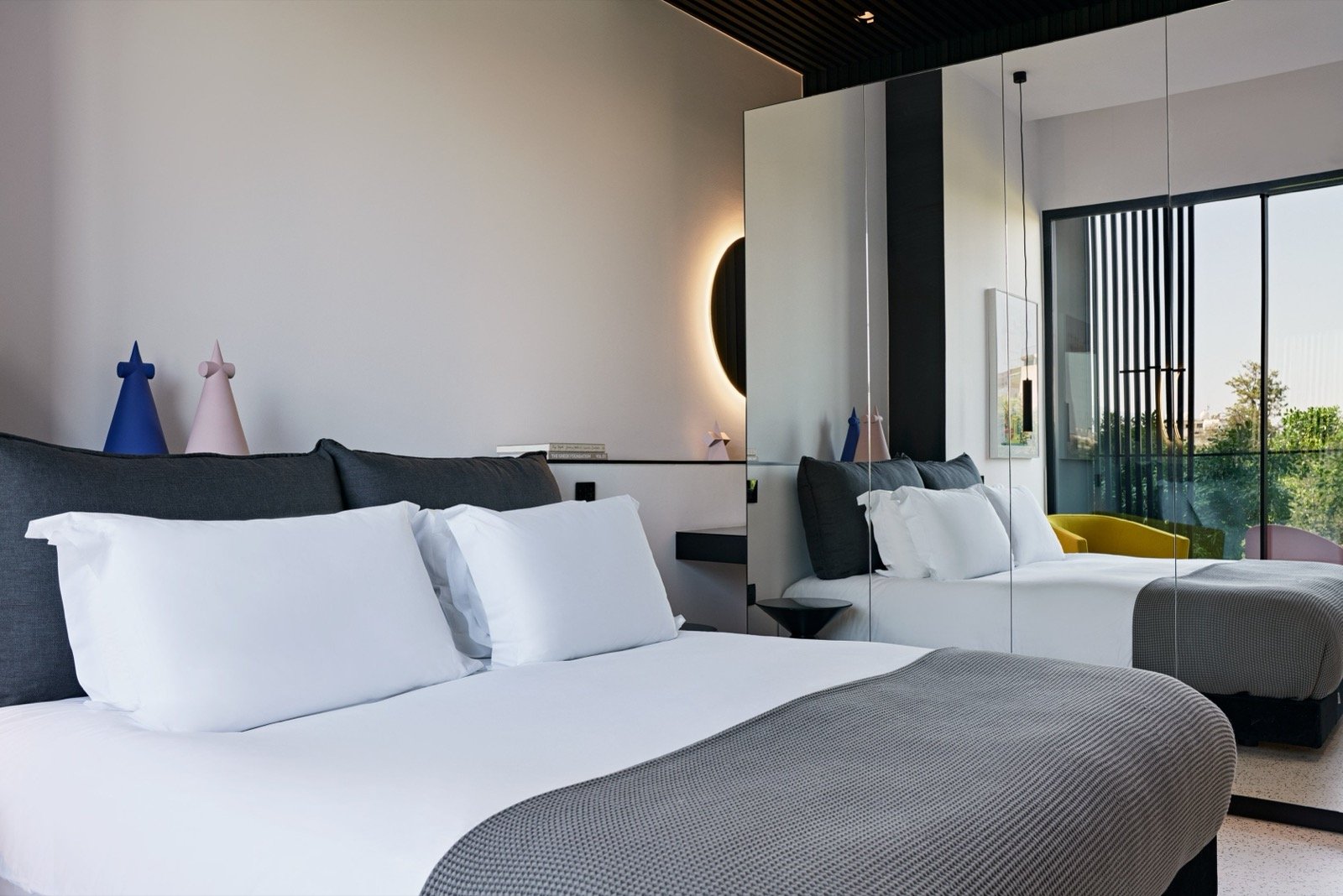 An Iconic room with a low black bed, mirrored wardrobe and a view over Nicosia