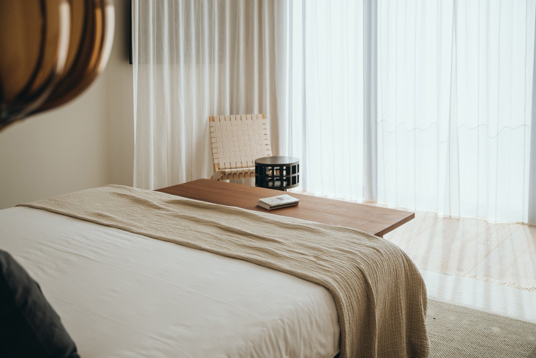 A pared-back room in terracotta and linen tones behind sheer curtains