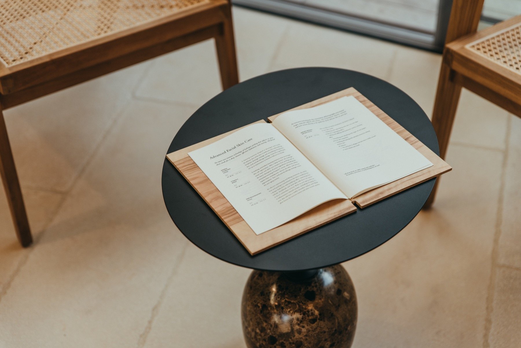 The spa treatment menu on a dark stone side table