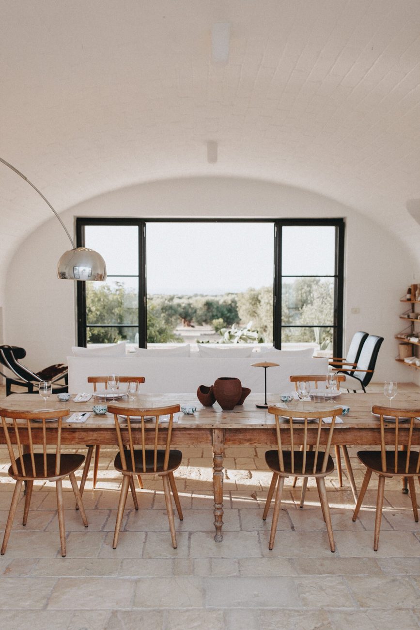 The vaulted dining room with its long wooden table and a window onto the olive grove