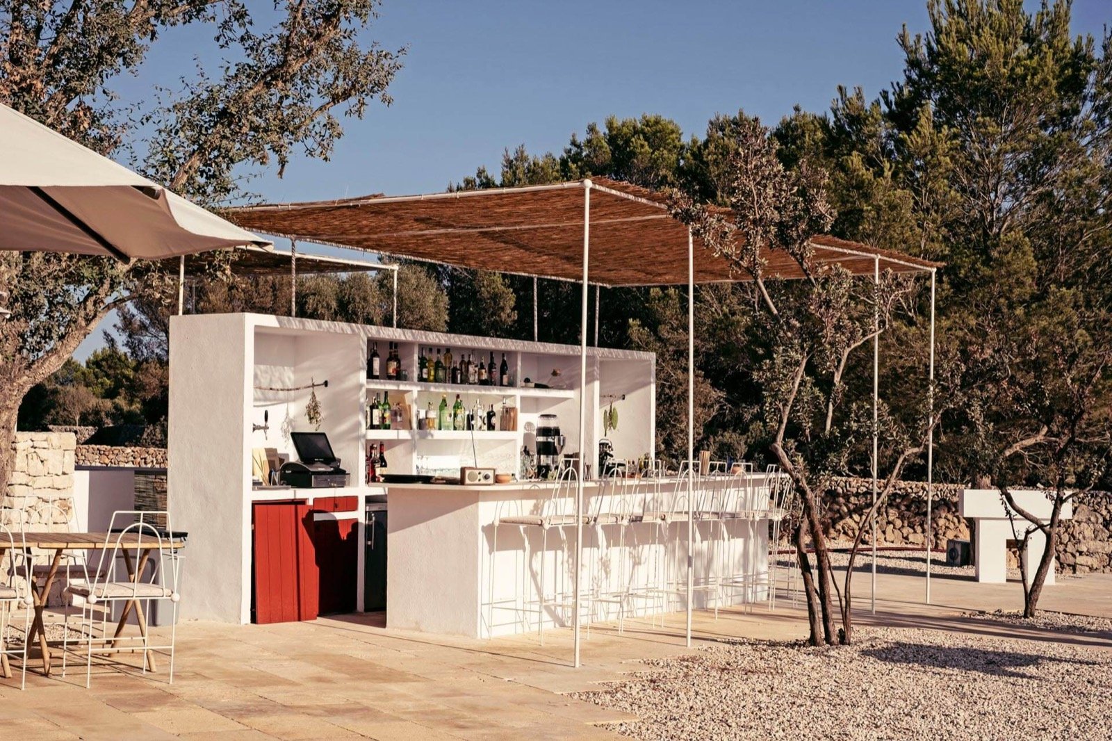 The open-air cocktail bar under a canvas awning among the olive trees