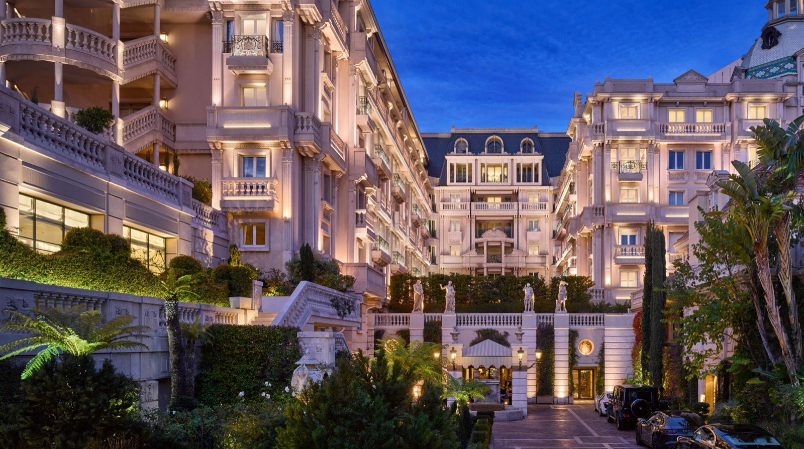 The Hôtel Métropole's Belle Époque facade and garden of statues, lit at dusk
