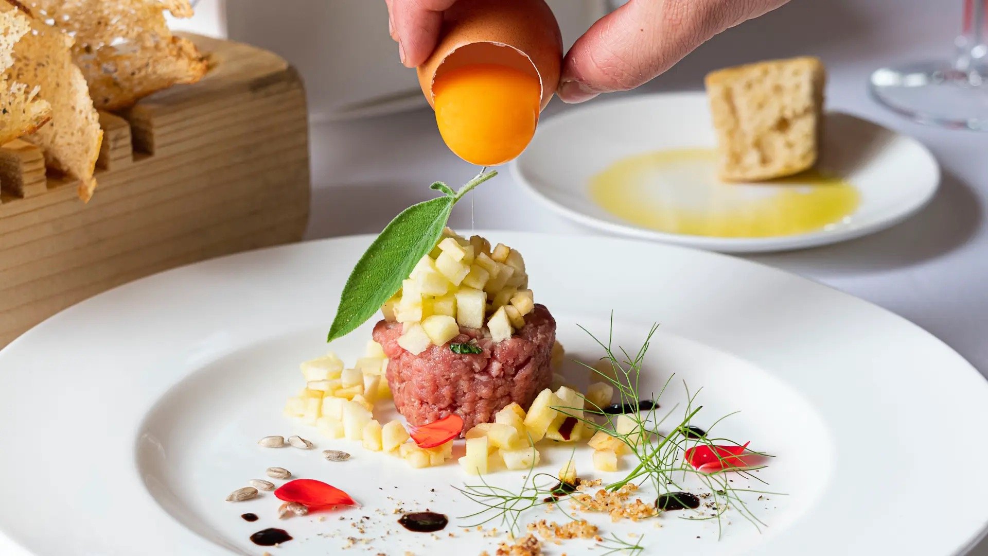 A plated dish at the estate table, finished with egg yolk and herbs
