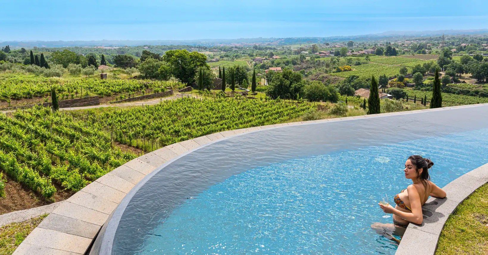 An infinity pool above the vineyards, the Ionian in the distance
