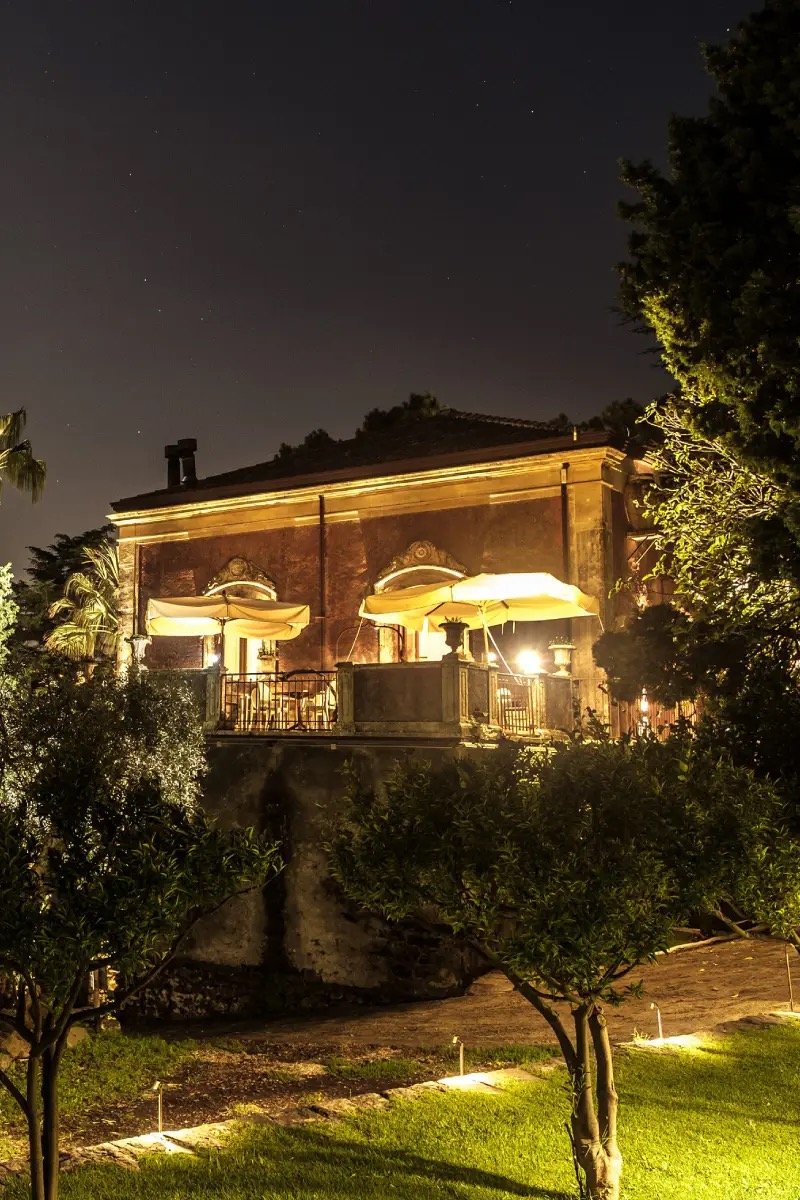 The 18th-century manor lit at night above the garden