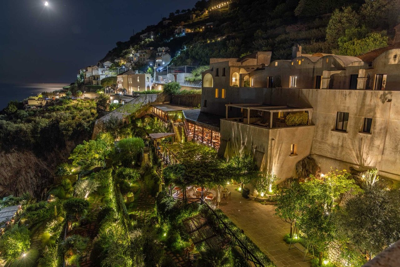 The monastery lit at night above the coast