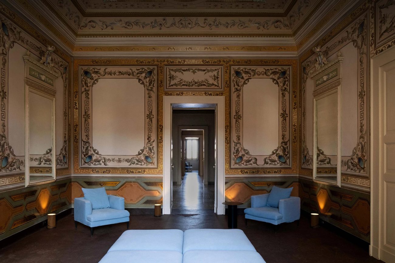 A frescoed salon left bare but for two pale blue armchairs