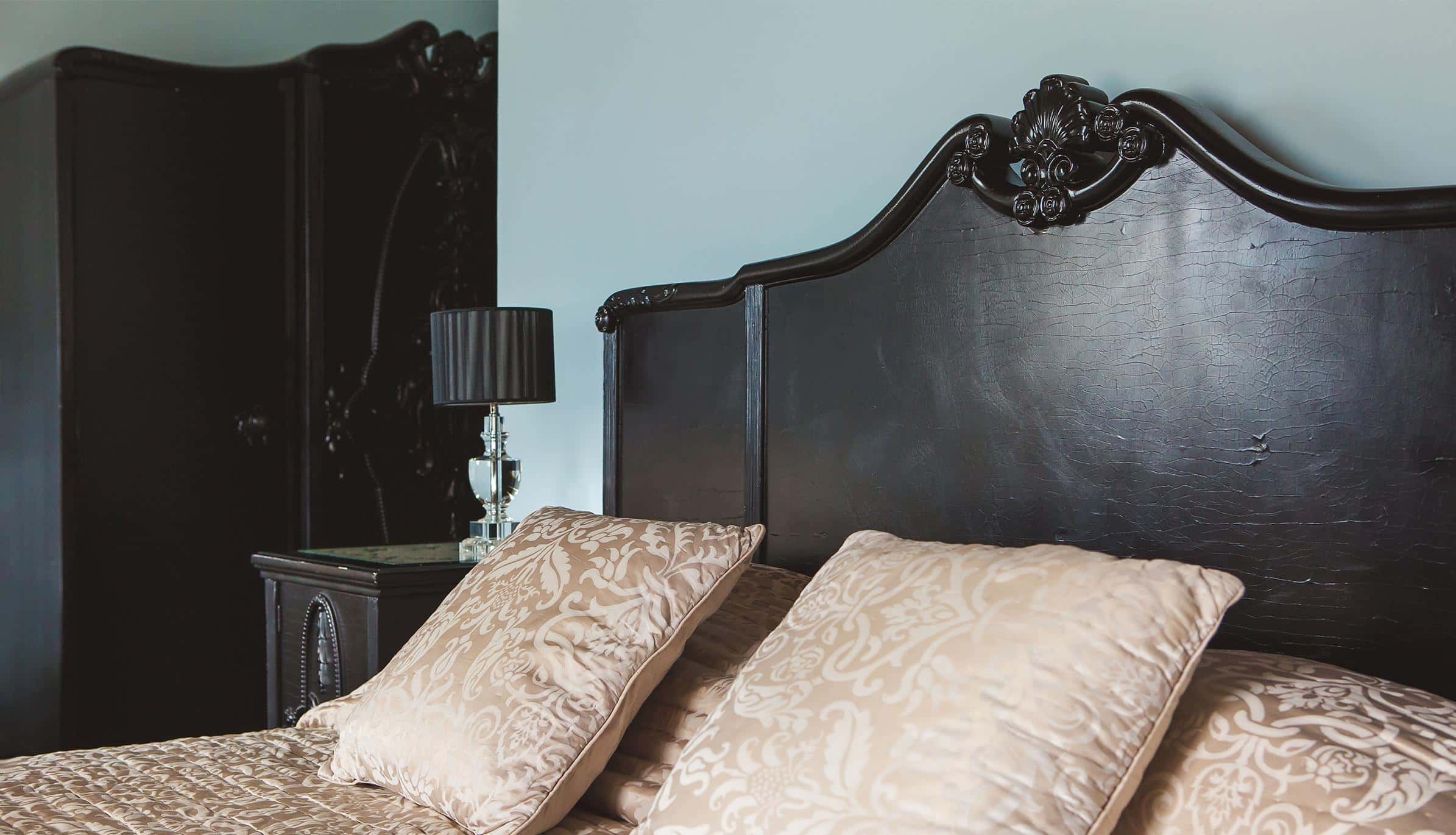 A room with an antique carved bed against exposed stone
