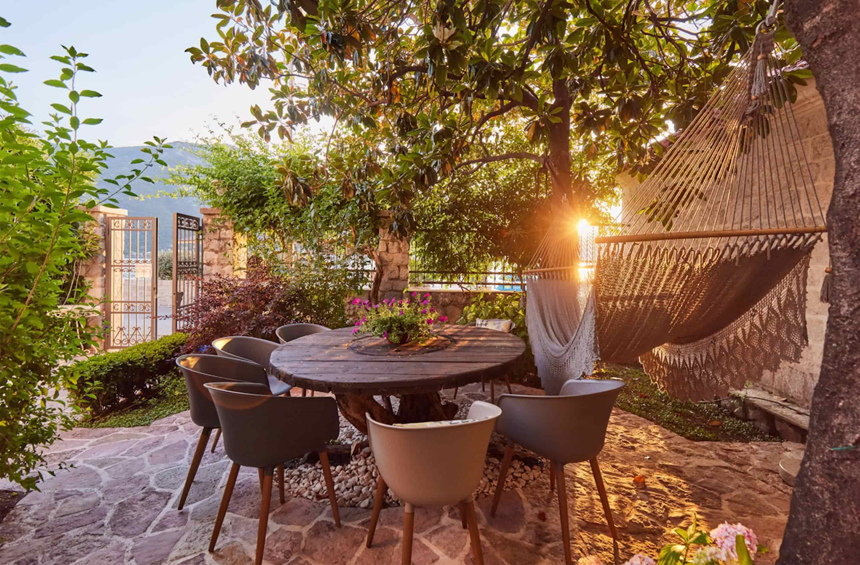 A garden dining table and hammock under the trees at dusk