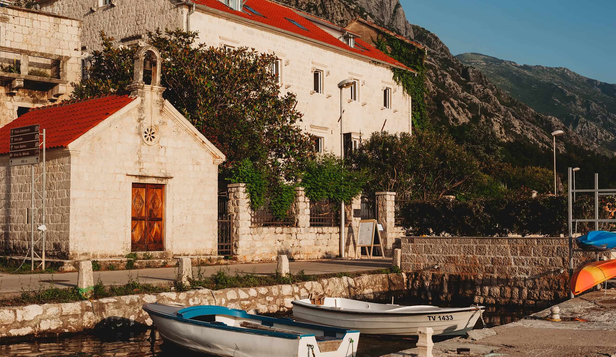 A small stone chapel and fishing boats on the Dobrota waterfront