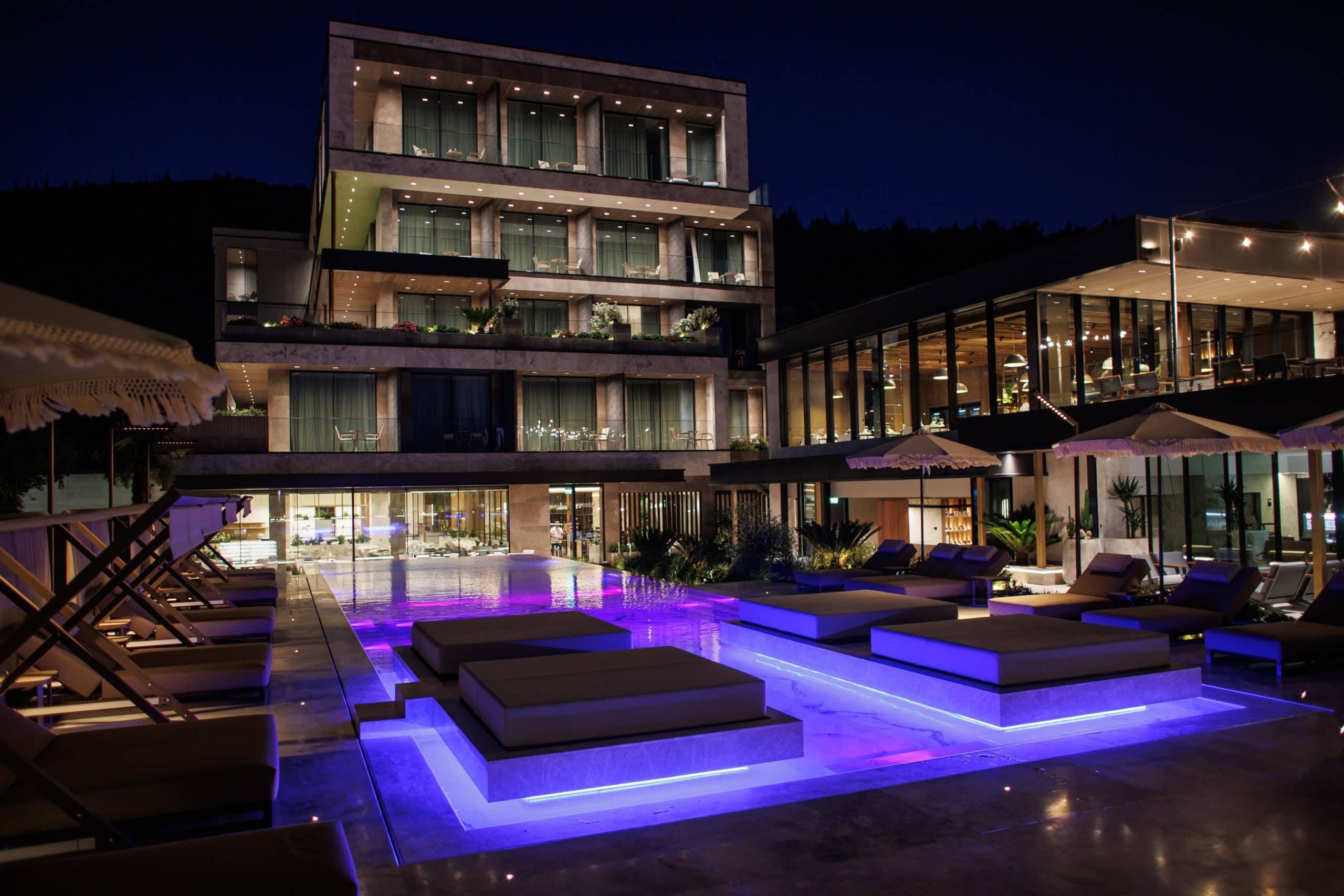 The stepped terraces lit at night above the pool, each floor set back from the one below