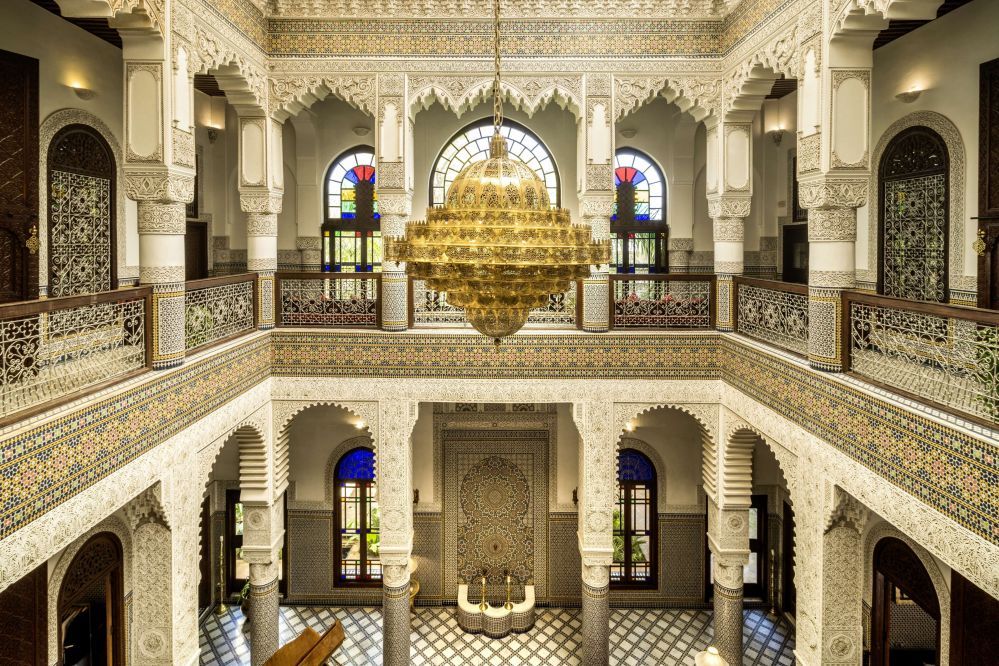 The grand interior courtyard, carved galleries and stained glass beneath a gilded chandelier
