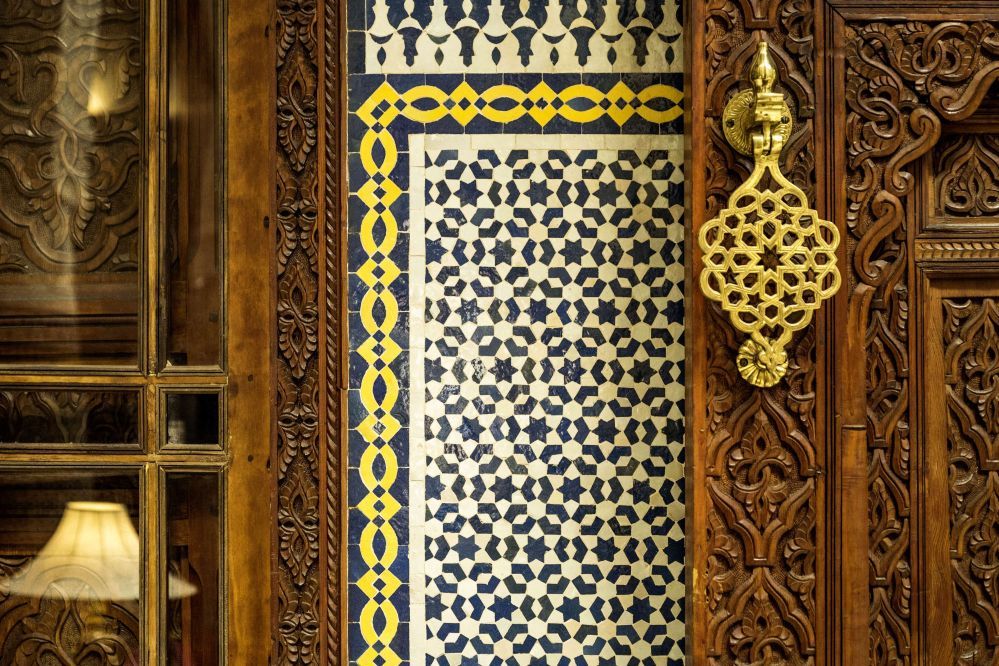 A detail of zellij tilework and a carved cedar door
