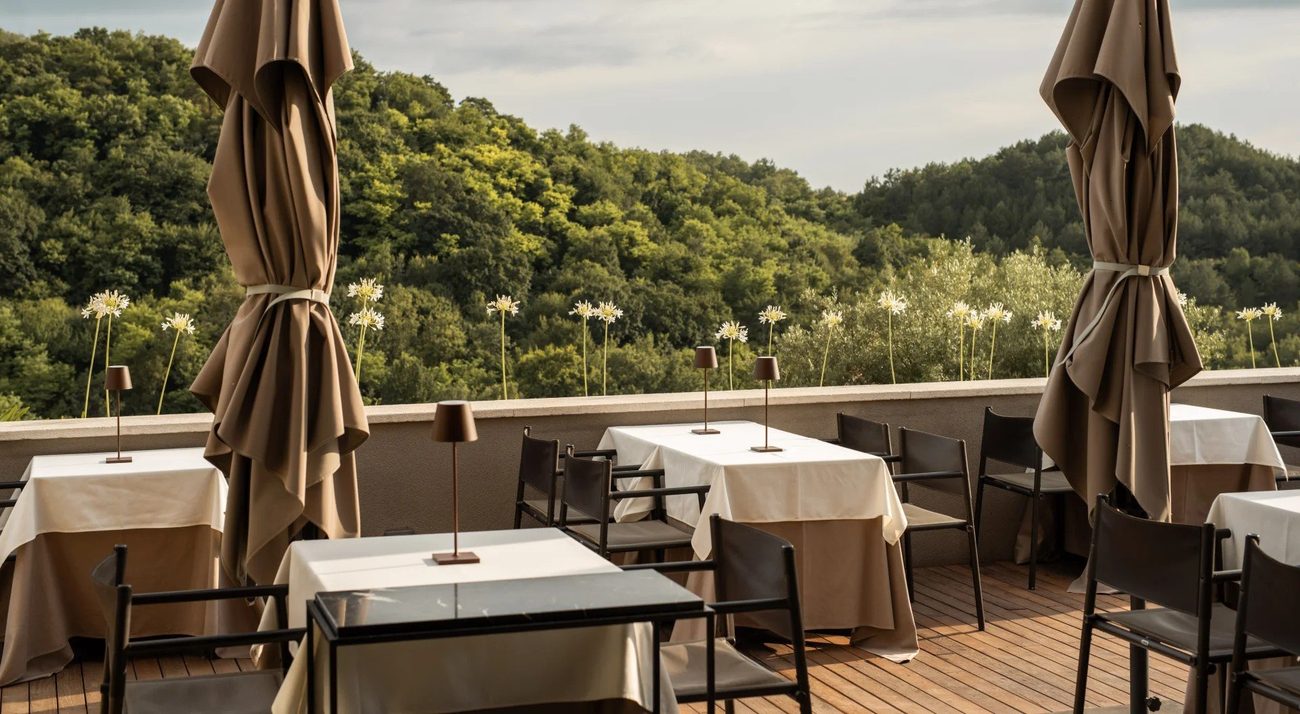 A dining terrace with tables set above the green hills of Istria